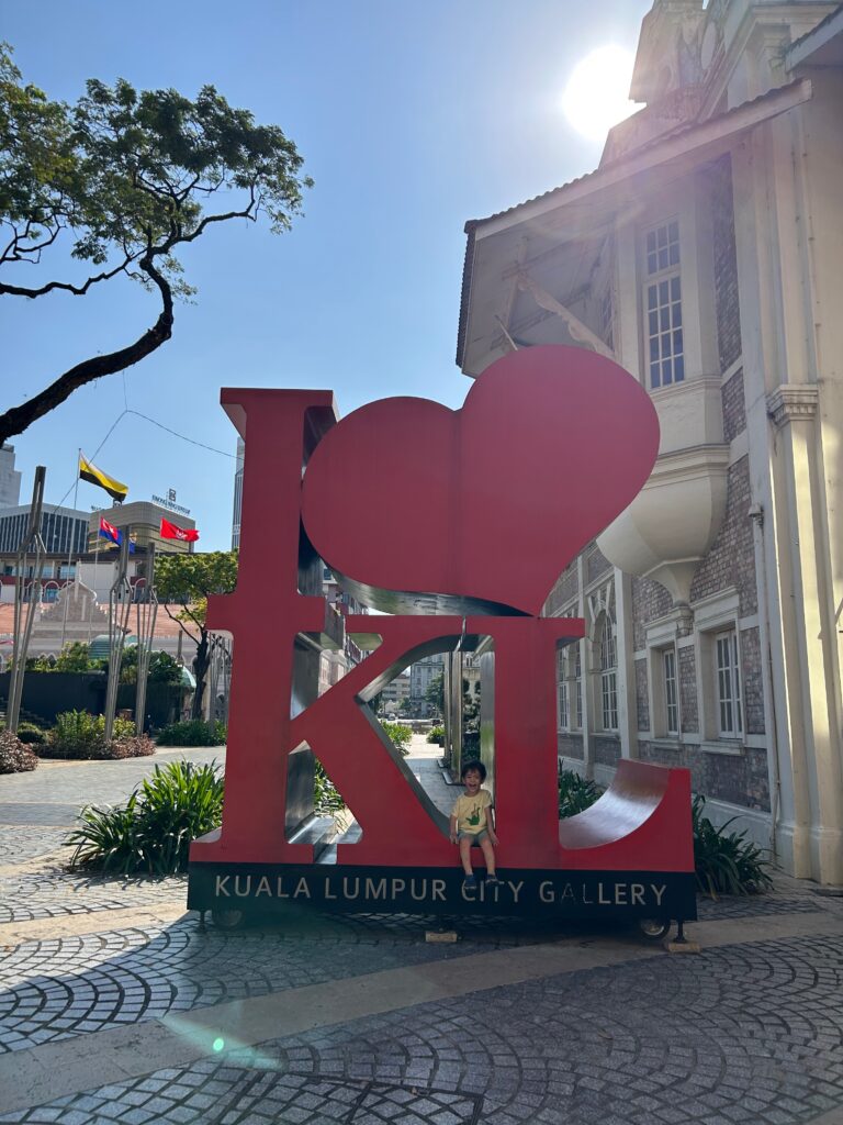 Young boy sitting in the I heart KL sign